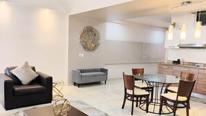 Een moderne woonkamer met een bank, een salontafel en een eethoek met een tafel en stoelen.