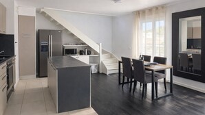 A modern kitchen with a built-in island, a dining area with a table and chairs, and a staircase leading to an upper level. - Large duplex for 8 guests, 2 bathrooms, near Disneyland & Paris (Champs-sur-Marne)
