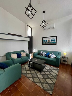 Ein Wohnzimmer mit zwei grünen Sofas, einem schwarzen Couchtisch und einem gemusterten Teppich.