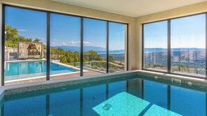 Ein moderner, überdachter Pool mit großen Fenstern und Blick auf die Berge.