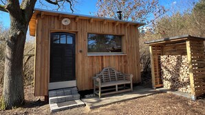 A small wooden cabin with a black door, a window, and a bench outside. - Vacation apartment in the old country station 2nd floor (Schwarz)