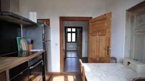 Eine kompakte Küche mit integriertem Backofen, Mikrowelle und Kühlschrank. Eine Holztür führt zu einem Flur mit einem Fenster.