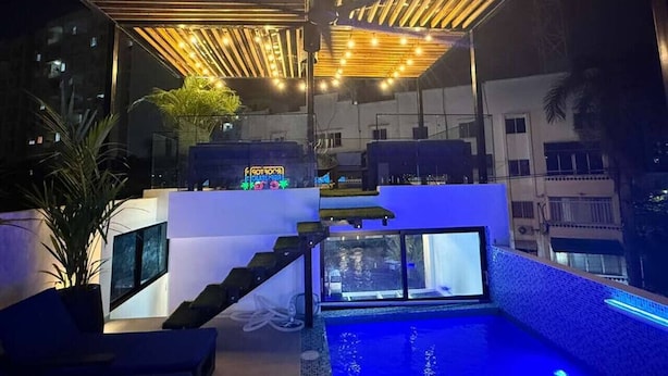 Ein moderner Poolbereich auf dem Dach mit Glasbrüstung, einer Treppe und stimmungsvoller Beleuchtung.