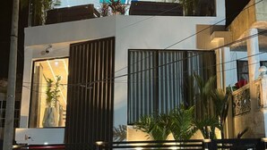 Un bâtiment moderne à deux étages, doté d’un balcon, de grandes fenêtres et d’un éclairage décoratif.