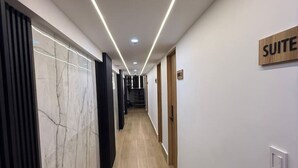 A modern hotel corridor with a wooden floor, white walls, and a sign indicating a suite. - Isla Mar Room – Peaceful Caribbean-Inspired Stay (Cartagena de Indias)