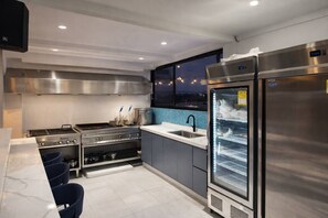 A modern kitchen with stainless steel appliances, a large refrigerator, and a window overlooking a cityscape. - Isla Mar Room – Peaceful Caribbean-Inspired Stay (Cartagena de Indias)