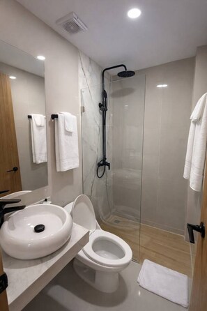 A modern bathroom with a glass-enclosed shower, a white sink, and a toilet. - Rooftop Royale – Modern Escape with Elevated Vibes (Cartagena de Indias)