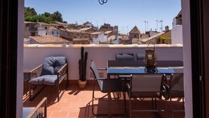 An outdoor patio with a table and chairs, a cactus, and a view of a town with terracotta roofs. - Los Yayos House - Segorbe Old Town (Segorbe)