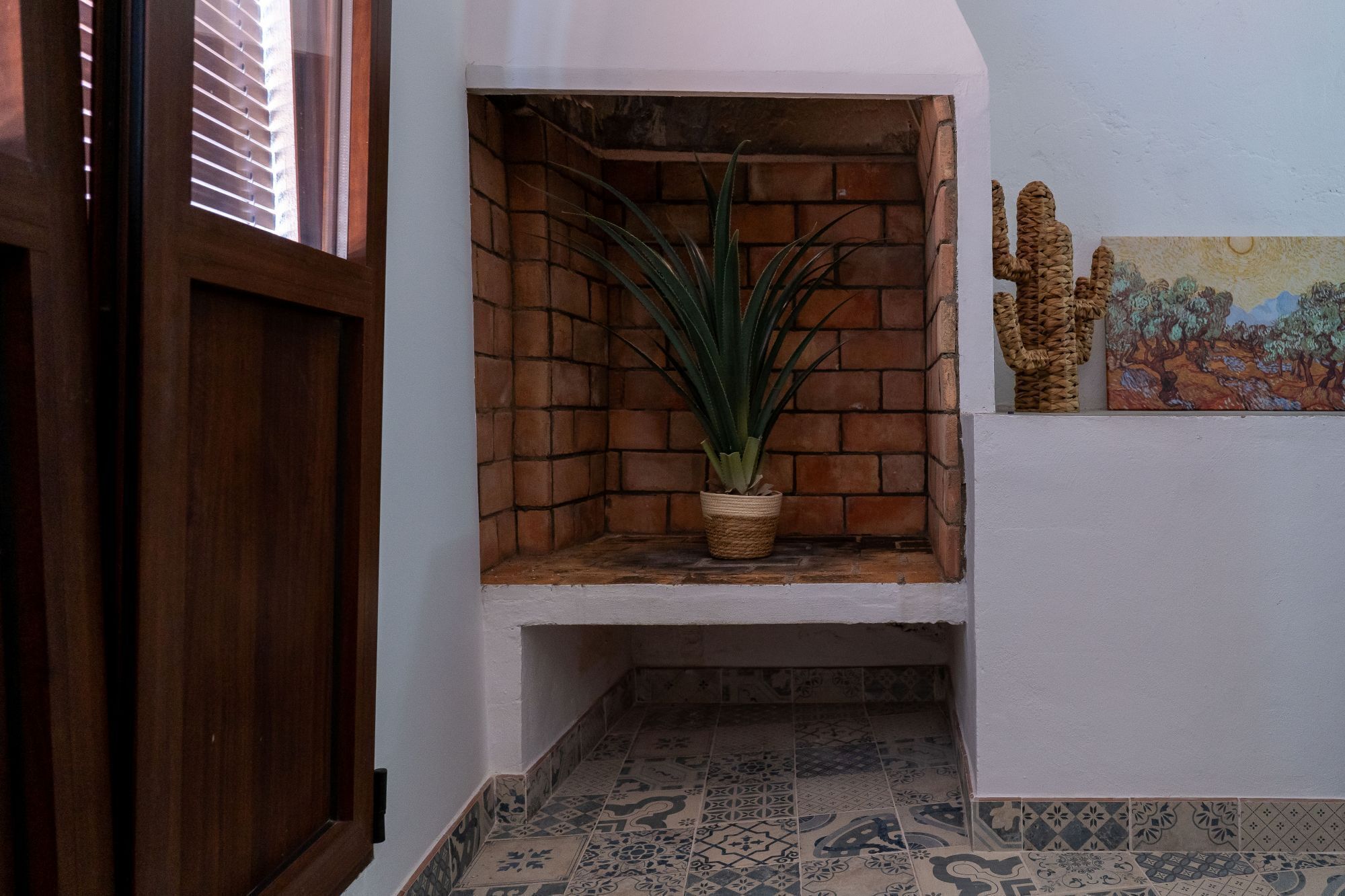 Un racó amb una planta en test, una petita estant i un quadre a la paret.