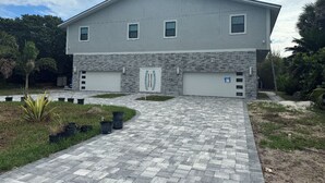 A two-story building with a garage, a paved driveway, and a stone base. - Stunning Ocean Views! 2-bedroom house, private beach in Melbourne Beach, FL (Melbourne Beach)