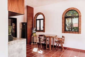 Eine Küche mit einem runden Holztisch, Stühlen, einem Kühlschrank und einem Wasserspender.
