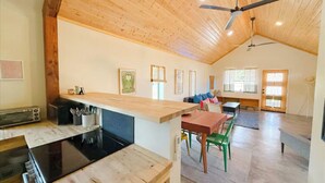 A spacious kitchen with wooden ceiling and walls, a dining area with a table and chairs, and a large window providing natural light. - La Palomita - Modern Casita in the Heart of Marfa TX (Marfa)