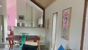 A dining area with a wooden table and chairs, a kitchen in the background, and a poster on the wall. - La Palomita - Modern Casita in the Heart of Marfa TX (Marfa)