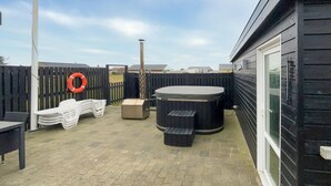 Un espace patio comprenant un jacuzzi, des sièges d’extérieur et une clôture.