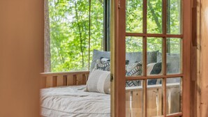 Letto con vista sugli alberi attraverso una finestra.