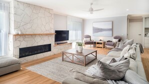 En moderne stue med en pejs af sten, et fladskærms-tv, en sofa og en loftventilator.