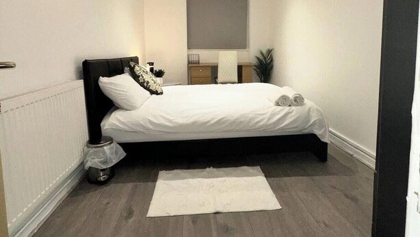 A modern bedroom with a bed, bedside tables, a radiator, and a window. - Quiet King’s Cross flat – Steps from the Station (London)