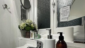 A bathroom with a white sink, a mirror, a towel dispenser, and a sign instructing guests to open the window after using the bathroom. - Quiet King’s Cross flat – Steps from the Station (London)