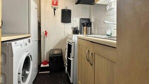 A compact kitchen with a washing machine, a small oven, and a sink. - Quiet King’s Cross flat – Steps from the Station (London)