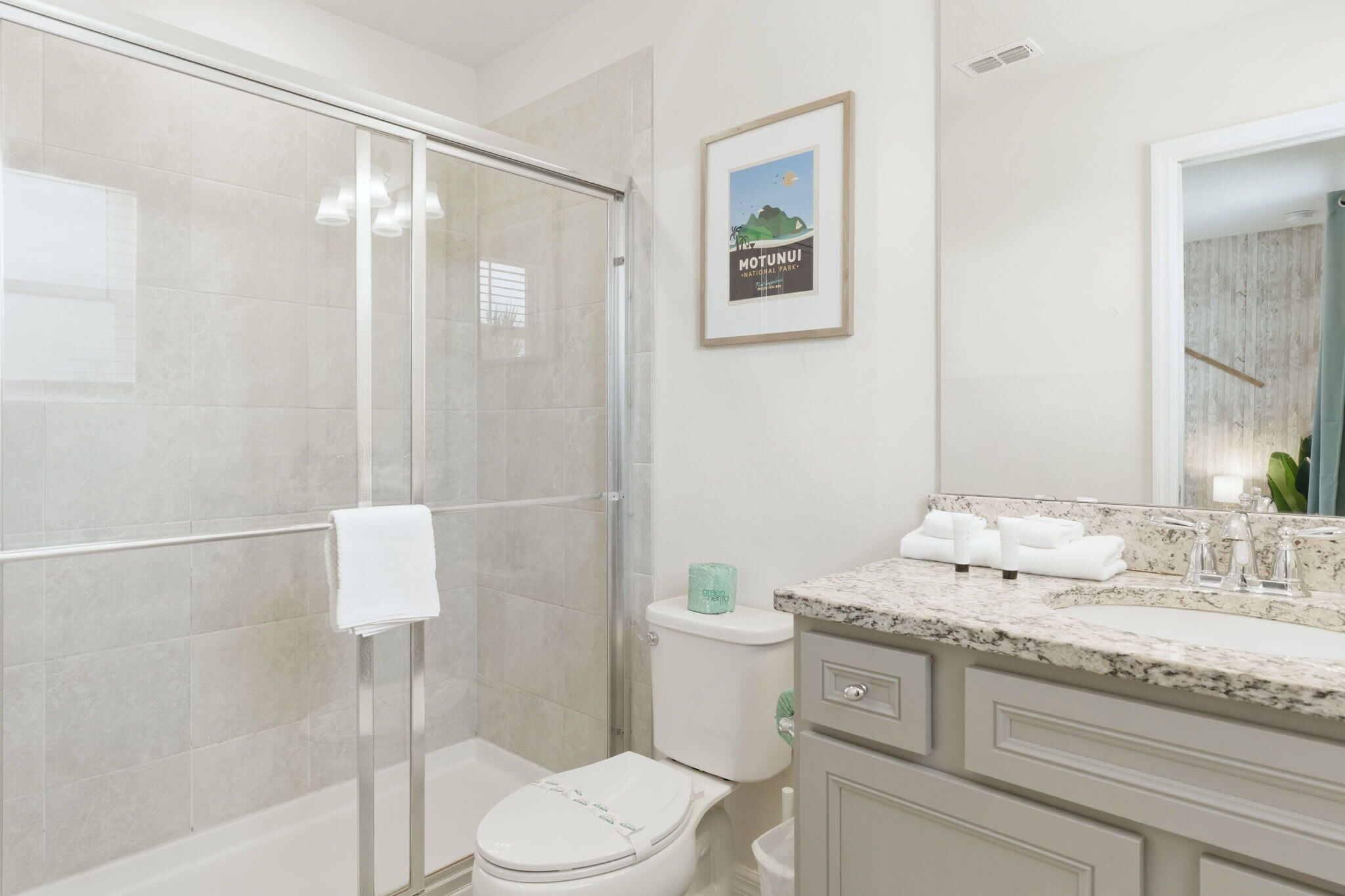 A modern bathroom with a shower, toilet, and sink.