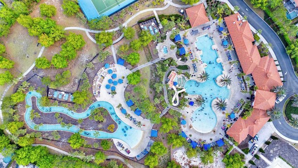 An aerial view of a resort with multiple swimming pools, a winding water slide, and a variety of outdoor seating areas. - Enchanted Palms Villa 7BR w Private Pool (Davenport)