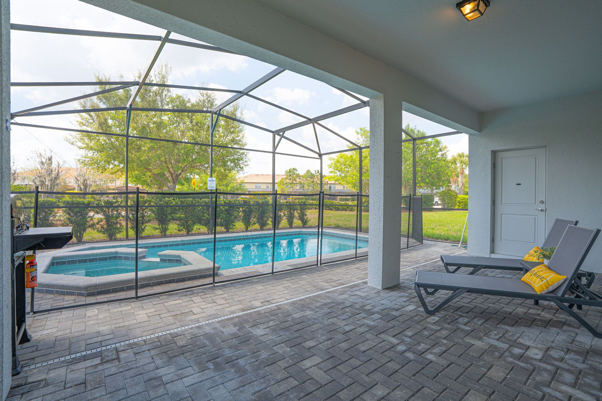 A covered outdoor area with a pool, lounge chairs, and a view of the surrounding landscape.