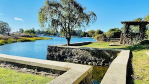 A stone bridge over a calm river, surrounded by grass and trees. - Luxury Waterfront Estate · Sleeps 18 · 45-Min Drive to FIFA World Cup Stadium (East Rutherford)