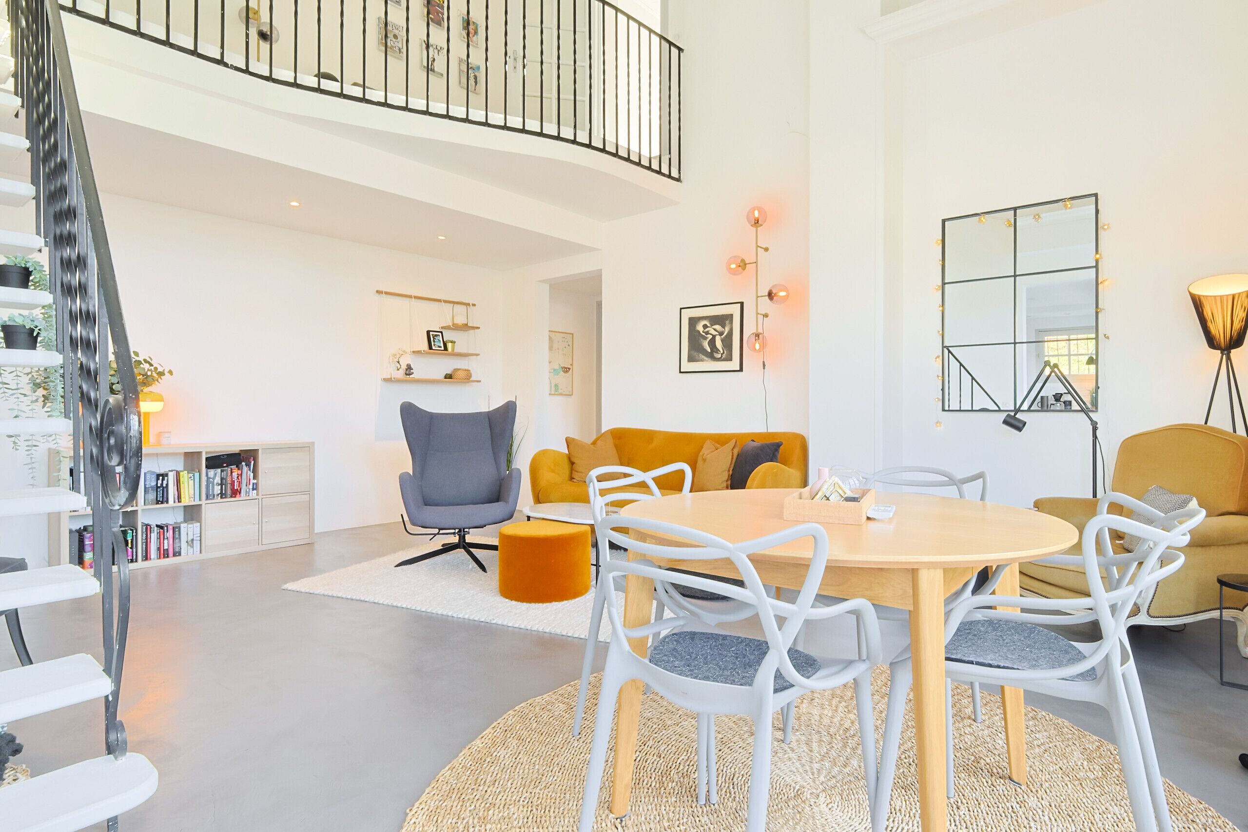 Un salon moderne avec un coin repas, un escalier et un balcon.