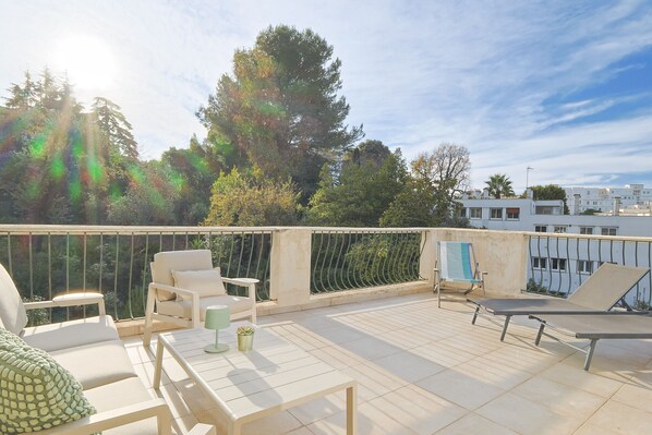 Terraço no telhado com área de estar ao ar livre, uma mesa e um vaso de planta.