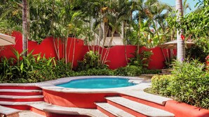 A swimming pool with red steps leading up to it, surrounded by lush greenery and a red wall. - Casa Roja · Whole Home with Pool, Terrace & Palapa · Local Sayulita (Sayulita)