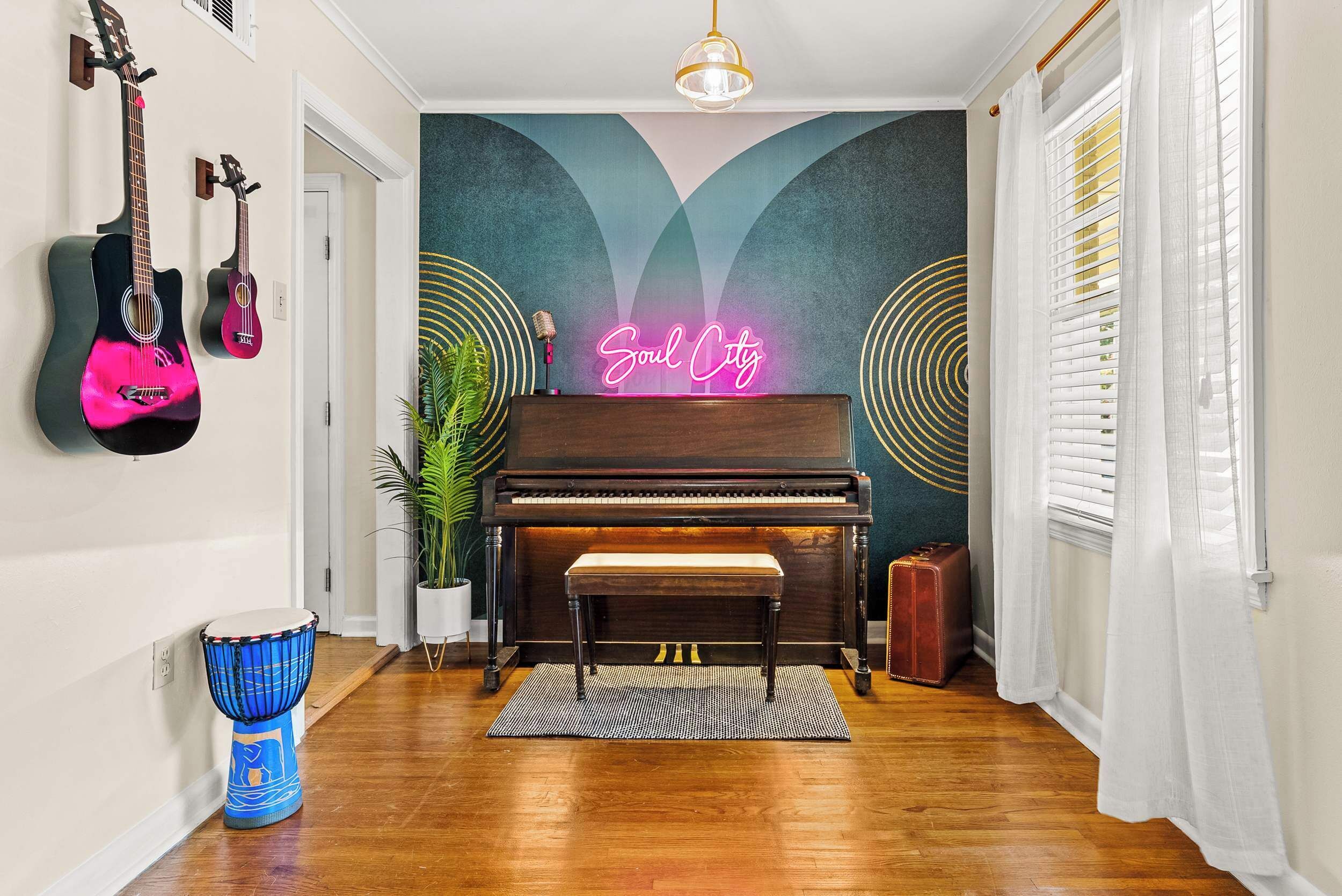 A hallway with a piano, a neon sign, a drum, and guitars on the wall.