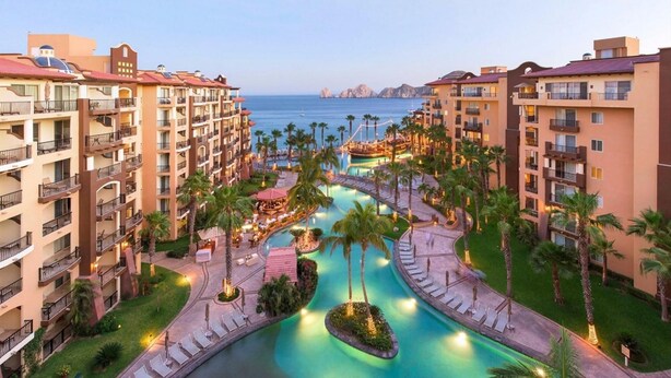 Un resort con diversi edifici, una zona piscina centrale e vista sul mare.