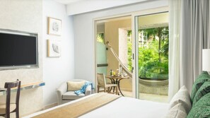 A hotel room with a bed, a desk, a chair, a table with a view, and a balcony with a chair and table.