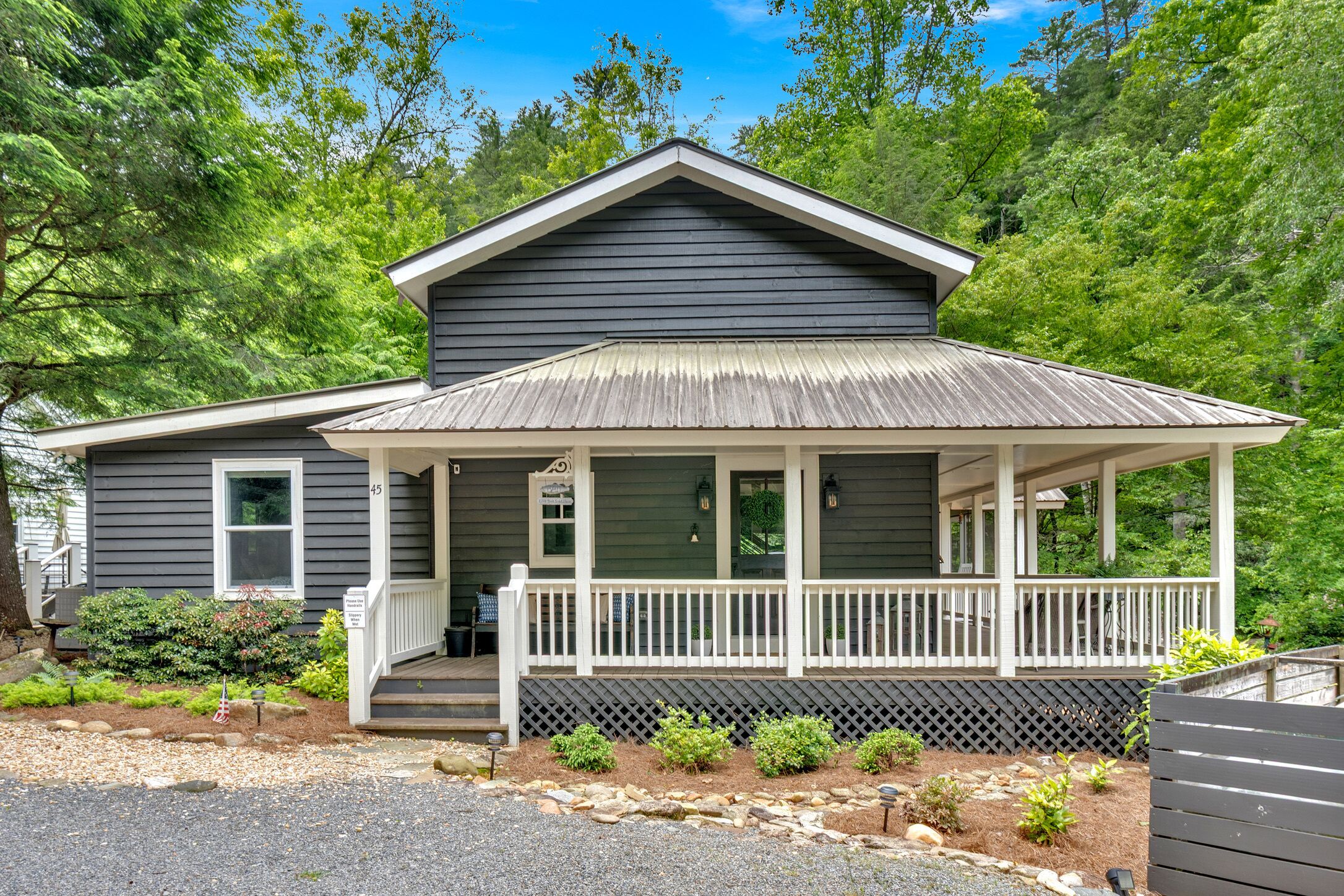 A two-story house with a front porch, a small garden, and a mailbox.