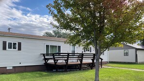 A single-story mobile home with a deck and a picnic table.
