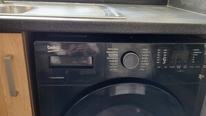 Una lavadora Beko ProSmart Inverter negra con un panel de control que muestra diferentes programas y temperaturas de lavado.
