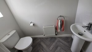 Un baño con inodoro, radiador y lavabo.