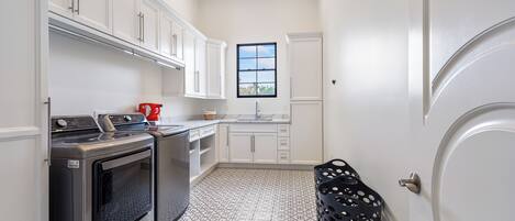 Una cucina compatta con mobili bianchi, forno integrato e finestra con vista.