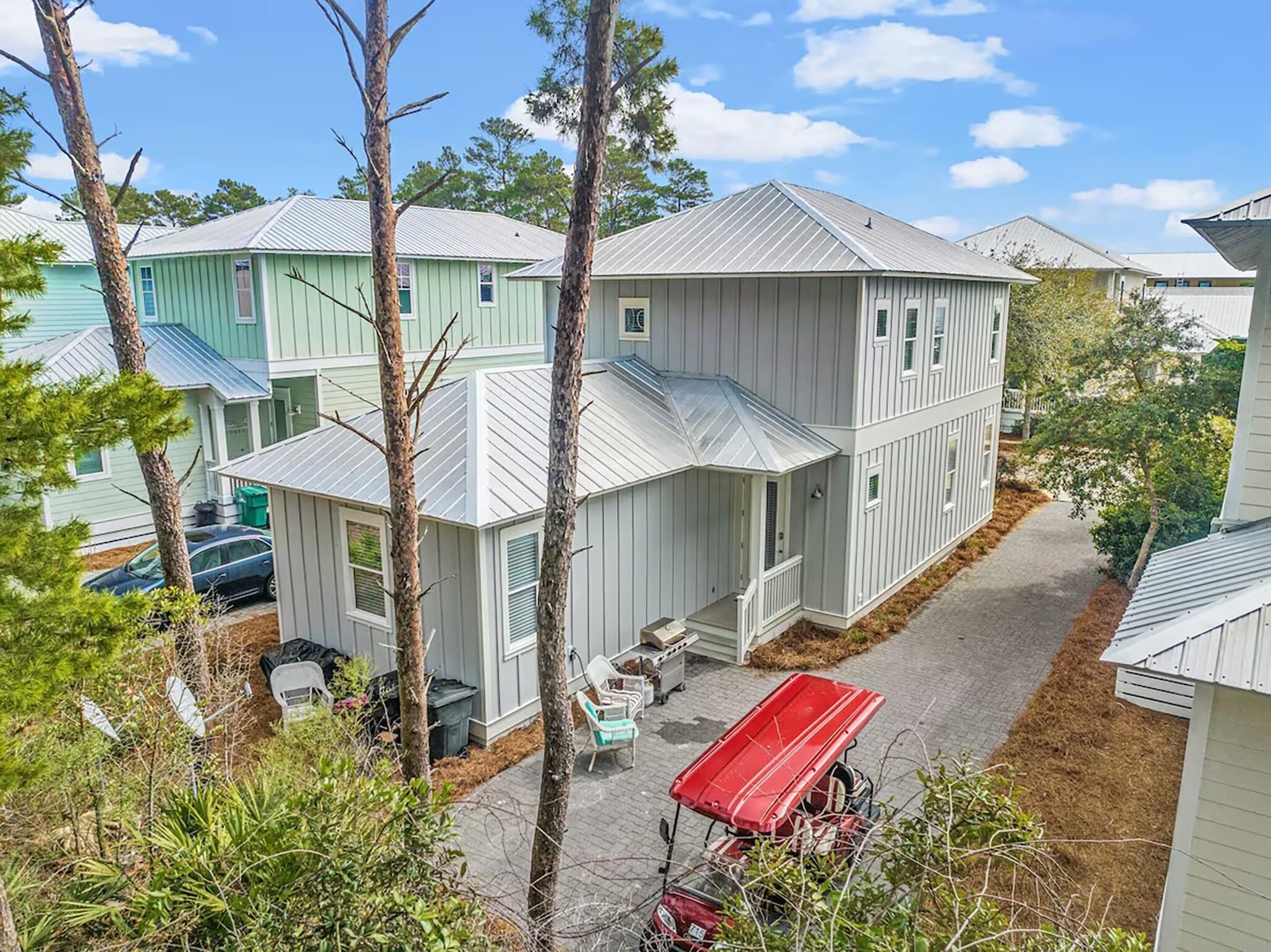 A two-story house with a covered porch and a red utility vehicle parked in front.