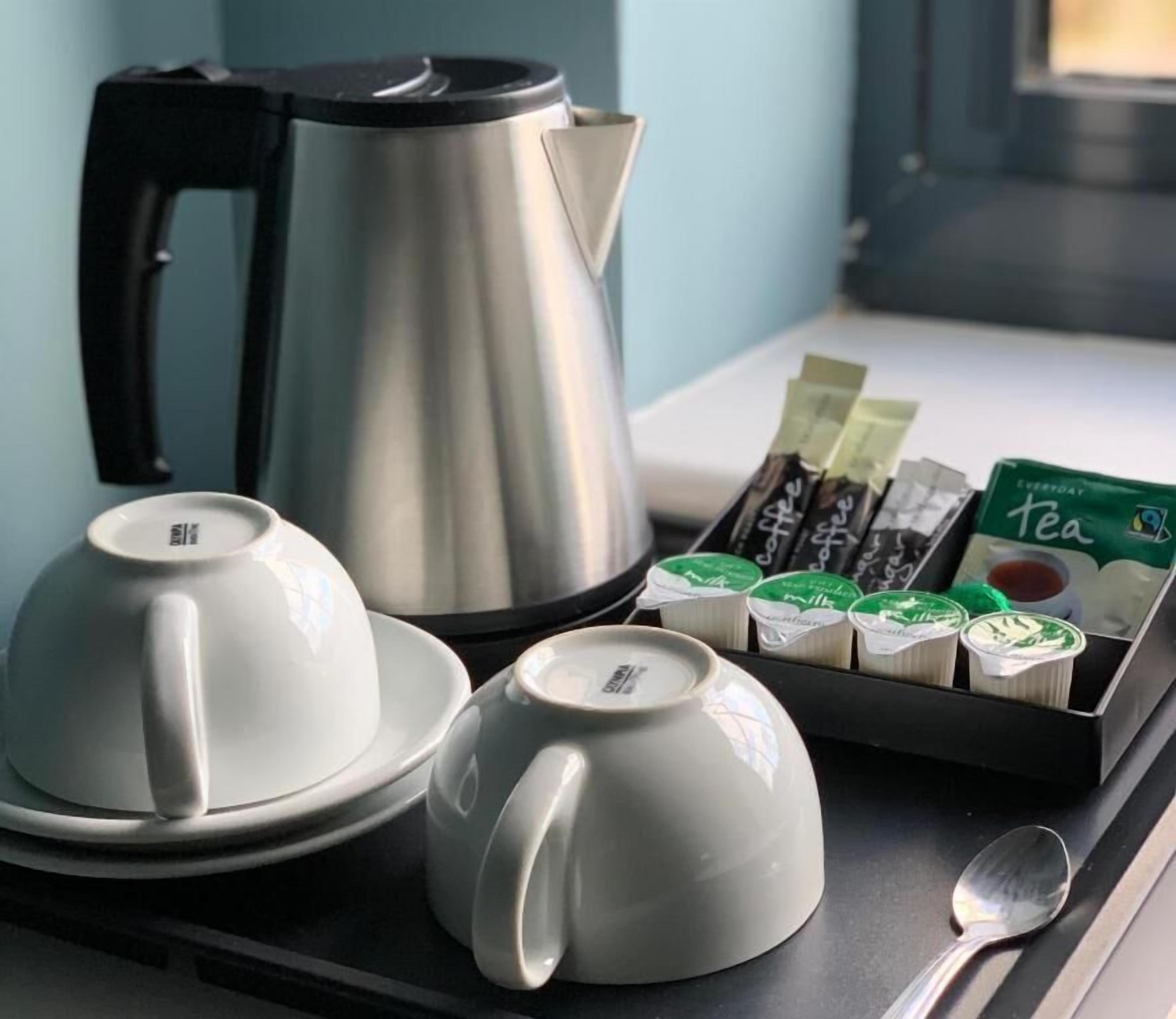 Un plateau contenant un service à thé, comprenant une théière, des tasses et des sachets de thé, posé sur une table.