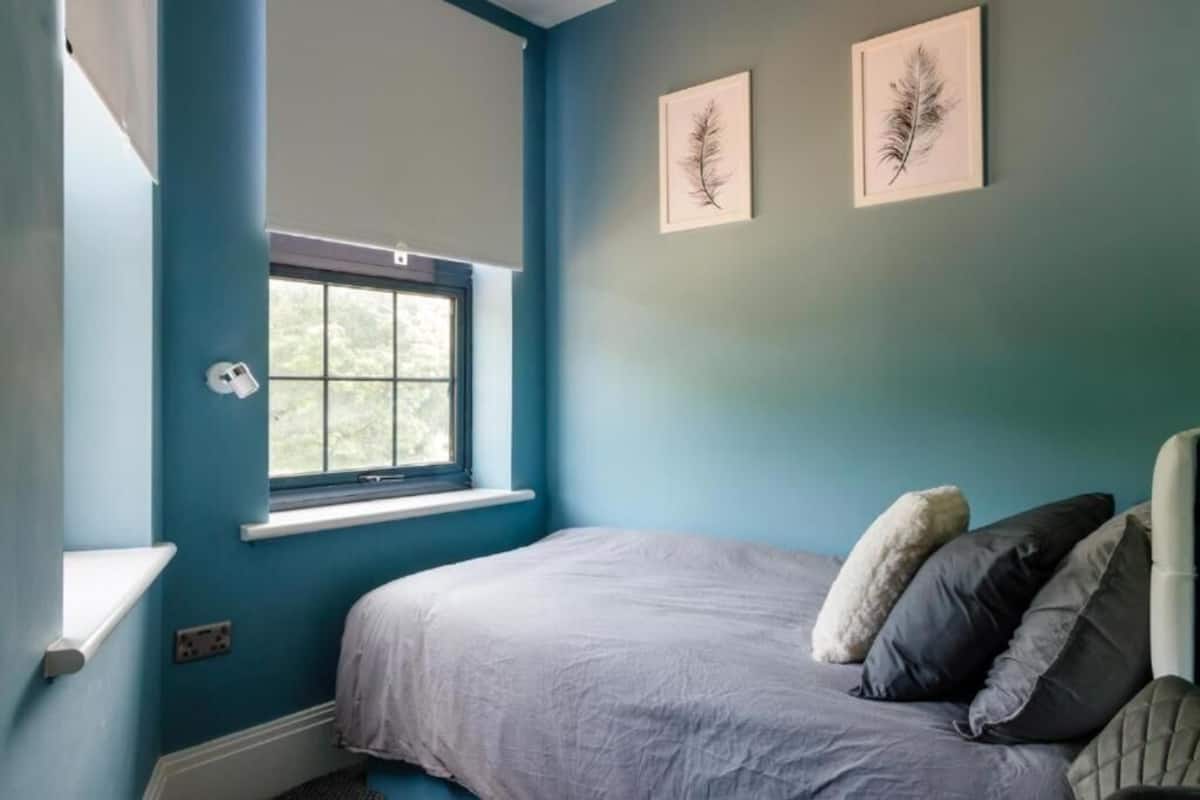 Un dormitorio con una cama individual, una ventana y dos cuadros enmarcados.