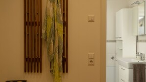 Un baño con pared de listones de madera, un banco, toallero y un espejo.