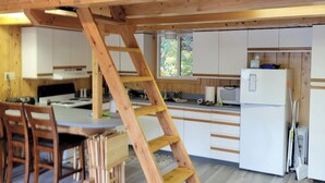 A wooden loft bedroom with a kitchen area below. - Remote Alaska cabin, located in the Kachemak Bay Park area of Tutka Bay. (Seldovia)