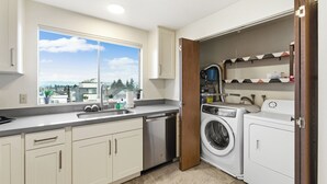 Una cocina moderna con un amplio ventanal, lavavajillas integrado y lavadora.