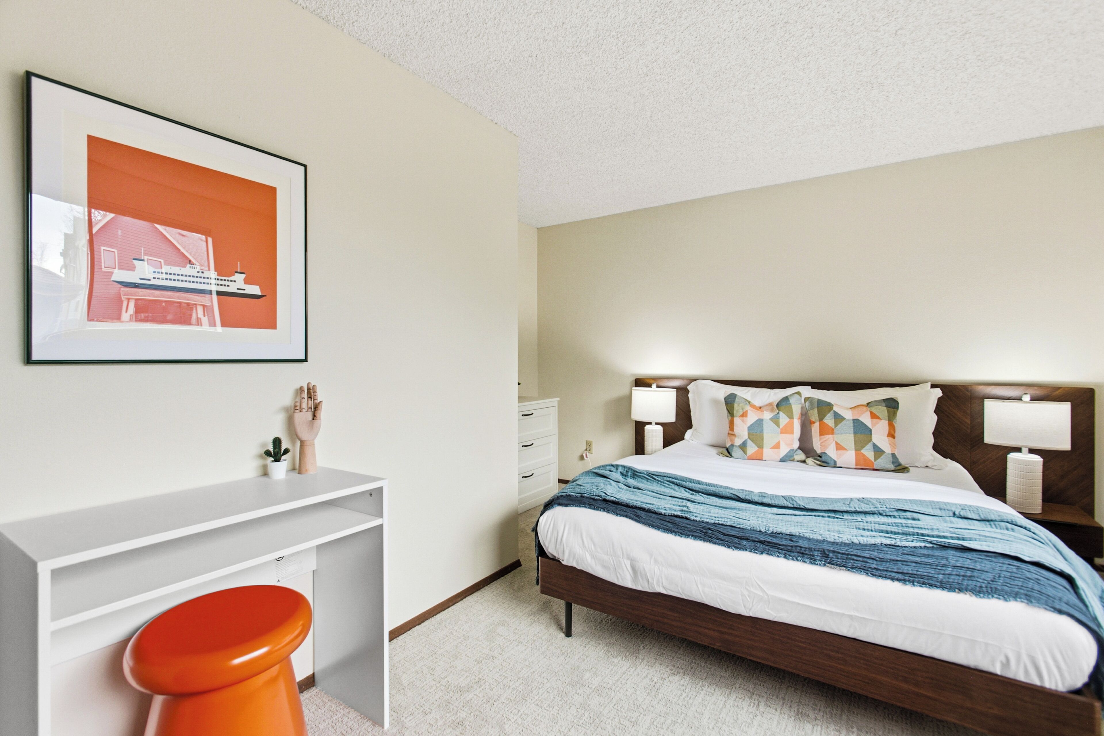 A bedroom with a bed, bedside tables, a desk, and a chair.