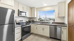 Una cocina moderna con electrodomésticos de acero inoxidable, muebles de cocina color beige y un amplio ventanal con vistas a la ciudad.