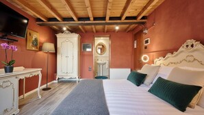 A bedroom with a wooden ceiling, a bed with green pillows, a white dresser, a TV, and a mirror. - v-nice rooms (Venice)