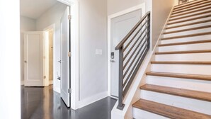 Een gang met een houten trap en een deur naar een andere kamer.