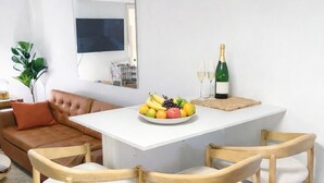 Una cocina moderna con encimera blanca, sillas de madera y un frutero.
