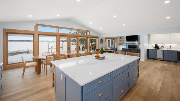 A spacious kitchen with a large island, wooden dining table, and chairs. - Long Lake Haven | 4BR | Waterfront | Boat Rental (Traverse City)